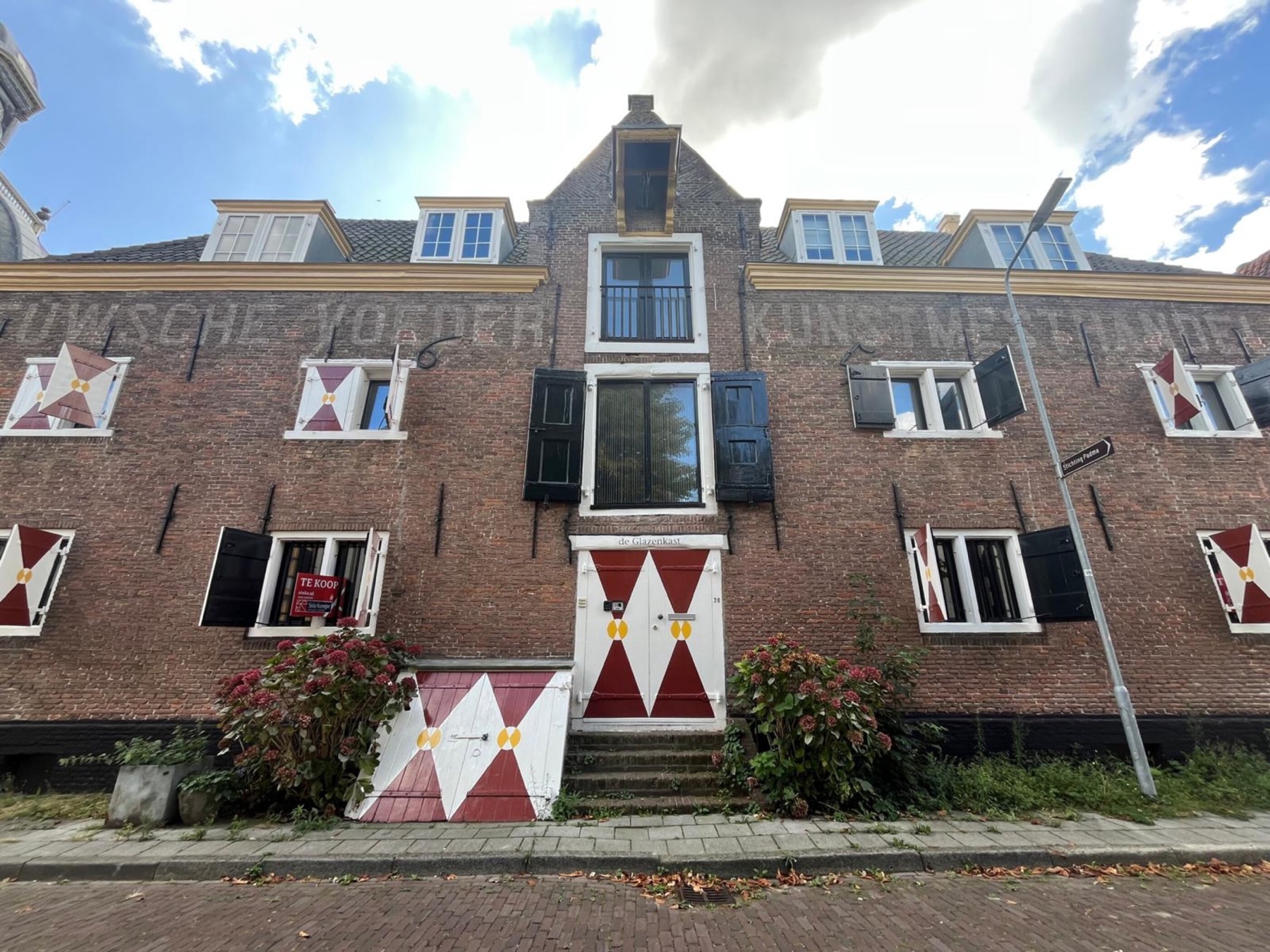De voorgevel van De Glazenkast met rood-witte luiken en gele stippen